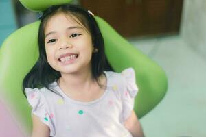 cerca arriba retrato de un caucásico niña teniendo un examen a el pediátrico dentista mientras sonriente a cámara foto