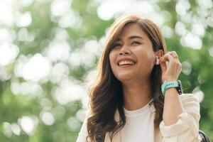 Portrait of happy young woman listening to music with wireless earphones outdoors photo