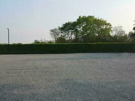 Parking lot sprinkled with gravel on tree bush nature background photo