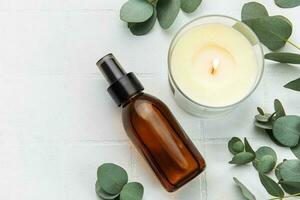 Bottle of natural cosmetic oil, aroma candle and eucalyptus leaves photo