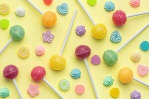 Sweet lollipops and candies on yellow background photo