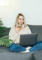 Young woman holding credit card and using laptop computer. photo