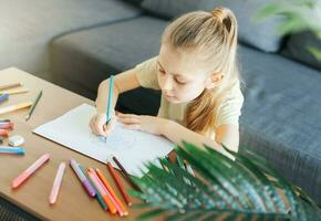 Child girl drawing with colorful pencils photo