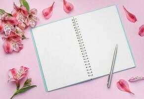 The notebook surrounded by pink Alstroemeria flowers and petals photo