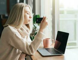 Young woman holding credit card and using laptop computer. photo