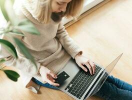 Young woman holding credit card and using laptop computer. photo