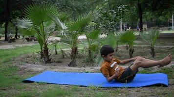 Aziatisch slim kind aan het doen yoga houding in de maatschappij park buitenshuis, kinderen yoga houding. de weinig jongen aan het doen yoga en meditatie oefening. video