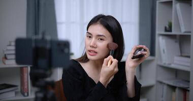 Beautiful young Asian woman blogger shows how to make up cosmetics at home photo