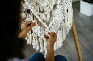 The production of boho-style panels is made of cotton threads of natural color in the macrame photo