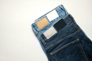 Two pairs of denim trousers with an empty leather label . photo