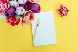 Top view of yellow desk with blank notebooks mockup with pencil and tulips. notebook. Place for text photo