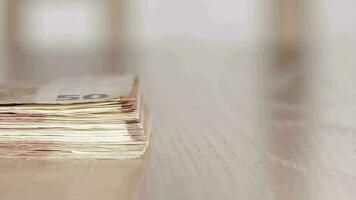 Pile of banknotes of 50 euros on a table. Extreme closeup video