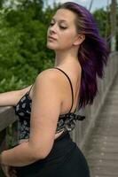 young woman with purple hair on a bridge in the wind photo