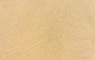 Sand Beach Texture Background in Summer, Top view Brown Sandy Rough Surface with Wave Ripple of Sea Water with copy space for Summer banner design,Natural Sand Stone by the Sea photo