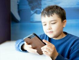 Education concept,School kid using mobile phone readying story from internet,Boy studying online learning at home,Child using cell phone playing game or chatting with friends, Homeschooling photo