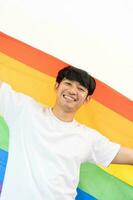 Cheerful young man wrapped in rainbow flag enjoying isolated on white background. Homosexual lgbtiq concept, rainbow flag, celebrating parade. Copy space. photo