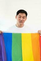 Cheerful young man wrapped in rainbow flag enjoying isolated on white background. Homosexual lgbtiq concept, rainbow flag, celebrating parade. Copy space. photo