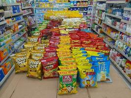 Lombok Island, Indonesia - June 16th, 2023. Various local and imported brands of flavoured chips and snacks on store shelf photo