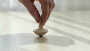 Man hand moving a spinning top on a table. Closeup video