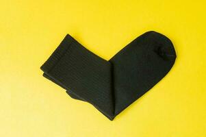 Black cotton socks are lying on a yellow table photo