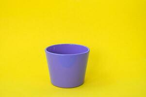 A purple flower pot stands on a yellow background. Empty flower pot photo