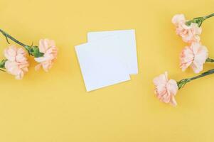 Bouquet of flowers yellow carnations lie with a notepad on a yellow background. View from above. photo