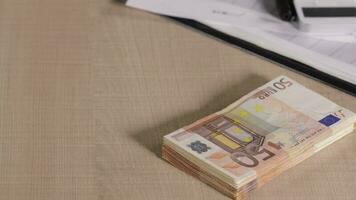 Pile of banknotes of 50 euros on a table with diagram and calculator. video