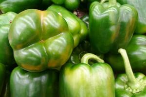 Stack of green bell peppers on a market stall photo