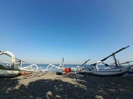Traditional wooden fishing boats and beautiful hilly beach in Lombok Island, Indonesia. Boats background on the beach, beautiful Indonesian beaches. Beach background. photo