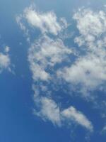 White clouds in the blue sky. Beautiful bright blue background. Light cloudy, good weather. Curly clouds on a sunny day. photo