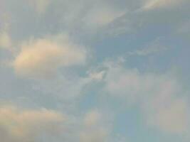 White clouds in the blue sky. Beautiful bright blue background. Light cloudy, good weather. Curly clouds on a sunny day. photo