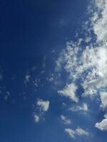 White clouds in the blue sky. Beautiful bright blue background. Light cloudy, good weather. Curly clouds on a sunny day. photo