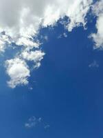 White clouds in the blue sky. Beautiful bright blue background. Light cloudy, good weather. Curly clouds on a sunny day. photo