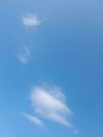 White clouds in the blue sky. Beautiful bright blue background. Light cloudy, good weather. Curly clouds on a sunny day. photo