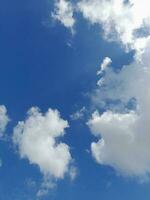 White clouds in the blue sky. Beautiful bright blue background. Light cloudy, good weather. Curly clouds on a sunny day. photo