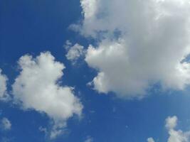 White clouds in the blue sky. Beautiful bright blue background. Light cloudy, good weather. Curly clouds on a sunny day. photo