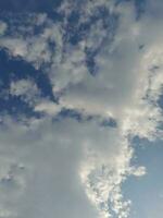 White clouds in the blue sky. Beautiful bright blue background. Light cloudy, good weather. Curly clouds on a sunny day. photo