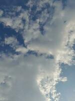 White clouds in the blue sky. Beautiful bright blue background. Light cloudy, good weather. Curly clouds on a sunny day. photo