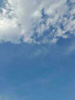 White clouds in the blue sky. Beautiful bright blue background. Light cloudy, good weather. Curly clouds on a sunny day. photo