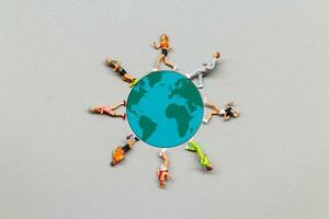 Miniature people standing on the globe with gray background photo