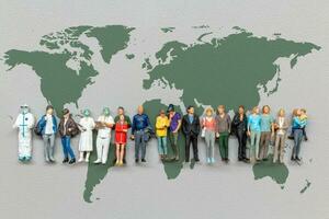 miniatura personas en pie en el mundo mapa con gris antecedentes foto