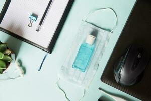 Top view of a desktop with notebooks, pens, and a laptop. Work from home using an online device, protection from coronavirus during the quarantine period. Protective masks and antiseptic. photo