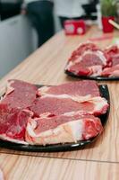 Raw beef meat for steak preparation. Raw beef sliced, preparation of meat for cooking steak at the culinary master class. Raw meat on a black plate. photo