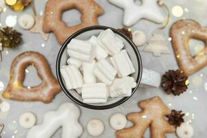 A cup of cocoa with marshmallows and Christmas gingerbread on the table, bokeh lights in the foreground. The concept of desserts and drinks during the Christmas holidays. photo