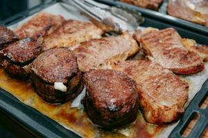 Cocinando filetes en un cacerola. Cocinando carne de vaca a el culinario Maestro clase. el manos de el cocinero en negro guantes. foto