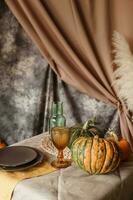 Autumn interior. A table covered with dishes, pumpkins, chair, casual arrangement of Japanese pampas grass. Interior in the photo Studio.