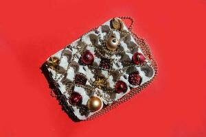 Christmas tree toys in the egg tray on a red background. Top view. The concept of New Year's holidays and Christmas. Red and gold colors. photo