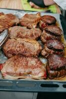 Cocinando filetes en un cacerola. Cocinando carne de vaca a el culinario Maestro clase. el manos de el cocinero en negro guantes. foto