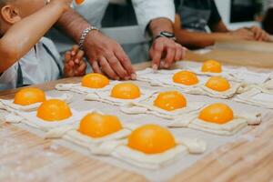 Preparing a dessert at a cooking master class. Baskets with peaches and strawberries, home cooking. Close-up, selective focus. Pastries, pies with peaches from puff pastry. photo