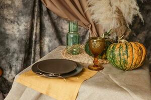 Autumn interior. A table covered with dishes, pumpkins, a relaxed composition of Japanese pampas grass. Interior in the photo Studio. Close - up of a decorated autumn table.